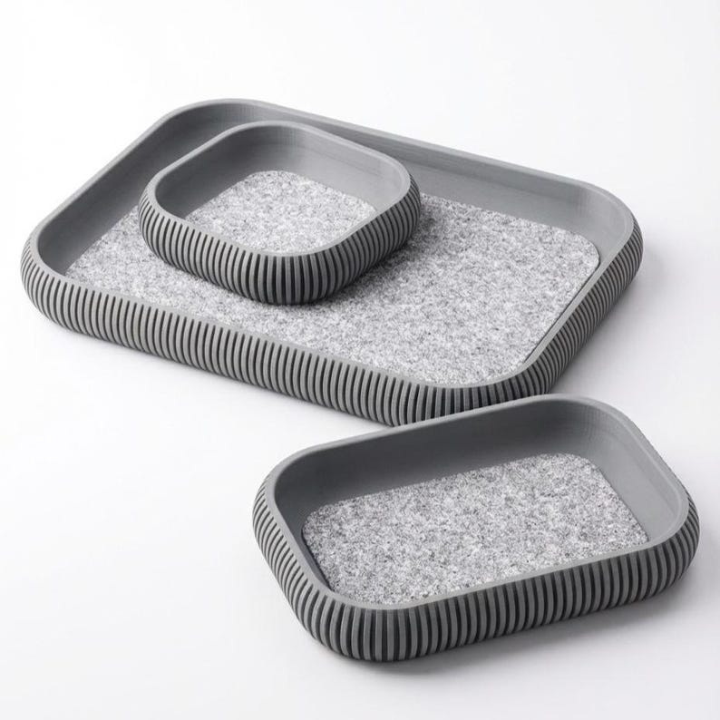 May include: A set of three gray trays with a textured, speckled interior. The trays are rectangular with rounded corners and ribbed sides. The smallest tray sits inside the medium tray, which sits inside the largest tray.
