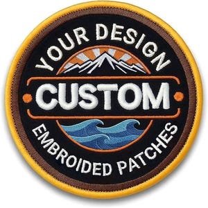 Op de afbeelding: Ronde geborduurde patch met de tekst "YOUR DESIGN CUSTOM EMBROIDERED PATCHES". Het ontwerp bevat een berg en een zon, met blauwe golven. De patch heeft een zwarte achtergrond, bruine en gele randen.