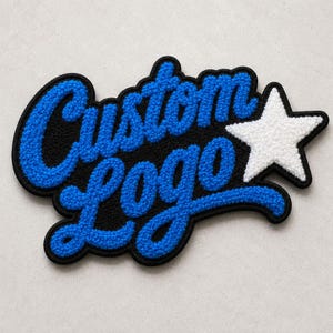 Puede incluir: Un parche personalizado con el texto Custom Logo en bordado de chenilla azul brillante con un borde negro grueso. A la derecha del texto hay una estrella de cinco puntas rellena de bordado de chenilla blanca, también delineada en hilo negro.