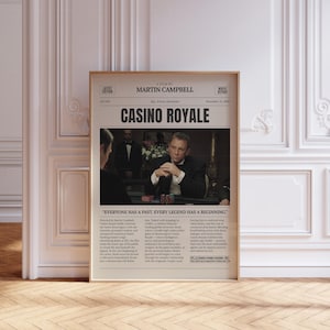 May include: A framed movie poster for "Casino Royale" featuring Daniel Craig. The poster has a newspaper-like design with the film's title in large font and a photo of Craig at a poker table. The text reads "Everyone has a past. Every legend has a beginning."