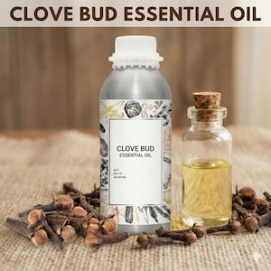 以下が含まれることがあります： クローブバッドエッセンシャルオイルが入った銀色の金属ボトルとコルク栓付きの小さなガラスボトル。乾燥したクローブバッドがボトルの周りに散らばっています。「CLOVE BUD ESSENTIAL OIL」の文字が画像上部にあります。