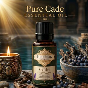 Puede incluir: Un frasco de 10 ml de aceite esencial de enebro de la marca Pure Peak Botanicals con etiqueta verde oscuro, texto dorado y emblema decorativo. El frasco se sitúa junto a una vela encendida en un soporte de bronce y un cuenco con bayas oscuras.