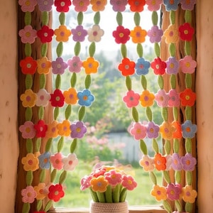 May include: A colorful, handmade crochet curtain with rows of vibrant flowers in shades of red, yellow, orange, pink, blue, and purple. The curtain hangs in a window, with a matching flower arrangement in a small pot on the windowsill.