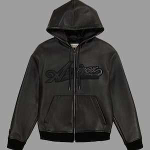 K&ouml;nnte beinhalten: Schwarze Leder-Kapuzenjacke mit Rei&szlig;verschluss, Kapuze und Vordertaschen. Die Jacke tr&auml;gt den Markennamen "Avirex" in erhabener, stilisierter Schrift auf der Brust. Die Jacke hat einen schwarzen gerippten Saum und B&uuml;ndchen.