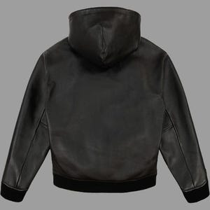 K&ouml;nnte beinhalten: Schwarze Lederjacke mit Kapuze, geripptem Saum und B&uuml;ndchen. Die Jacke hat einen durchgehenden Rei&szlig;verschluss und eine Kapuze. Die R&uuml;ckansicht zeigt die glatte Lederstruktur und das ma&szlig;geschneiderte Design. Ein klassisches Oberbekleidungsst&uuml;ck.