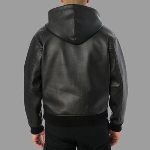 K&ouml;nnte beinhalten: Schwarze Lederjacke mit Kapuze, geripptem Saum und Manschetten. Die Jacke hat einen durchgehenden Rei&szlig;verschluss und eine Kapuze. Das Model tr&auml;gt eine schwarze Hose. Die Jacke ist ein klassischer Stil.