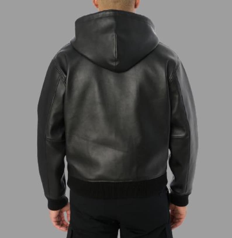 K&ouml;nnte beinhalten: Schwarze Lederjacke mit Kapuze, geripptem Saum und Manschetten. Die Jacke hat einen durchgehenden Rei&szlig;verschluss und eine Kapuze. Das Model tr&auml;gt eine schwarze Hose. Die Jacke ist ein klassischer Stil.