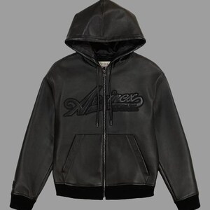 K&ouml;nnte beinhalten: Schwarze Lederjacke mit Kapuze, Rei&szlig;verschluss und K&auml;ngurutasche. Die Jacke tr&auml;gt den gepr&auml;gten Markennamen "Aviirex" auf der Brust. Die B&uuml;ndchen und der Saum sind gerippt. Ein klassisches Oberbekleidungsst&uuml;ck.