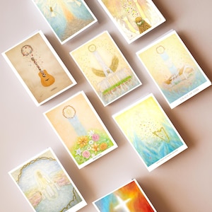 May include: A collection of watercolor art cards featuring spiritual themes. The cards depict angels, musical instruments, and floral arrangements in soft pastel colors. Some cards have text such as "Grace of God" and "Heaven".