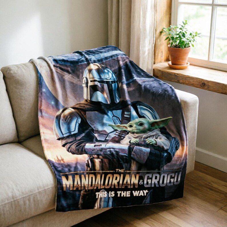 May include: A soft blanket with a graphic of The Mandalorian and Grogu from the Star Wars series. The blanket shows the characters in a detailed illustration with the text "THE MANDALORIAN & GROGU THIS IS THE WAY" at the bottom.