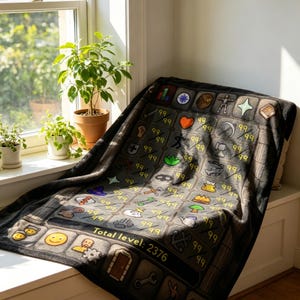 May include: A gray blanket with a video game interface design, featuring icons and the text "Total level: 2376." The blanket is draped over a window seat, with potted plants in the background. The design includes various icons and the number "99".