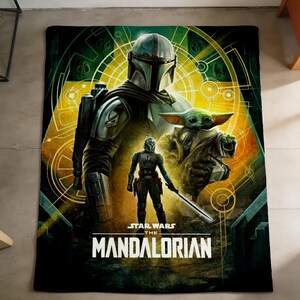 May include: A black blanket with a colourful illustration of characters from "The Mandalorian." The design includes the Mandalorian in armour, Grogu, and the show's title in white text. The background has a yellow and green geometric design.