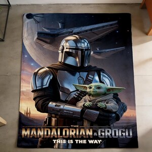 May include: A rectangular blanket featuring a scene from The Mandalorian. The image shows the Mandalorian holding Grogu, with a spaceship and planet in the background. The text "THE MANDALORIAN & GROGU THIS IS THE WAY" is at the bottom.