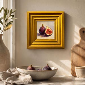 May include: A framed painting of two figs, one whole and one cut open, with a golden frame. The painting is displayed on a neutral wall. A ceramic bowl with figs and a cutting board are in the foreground.