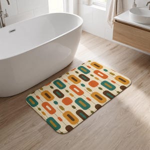 May include: A rectangular bath mat featuring a repeating pattern of rounded rectangles in shades of orange, teal, brown, and mustard yellow on a cream background, connected by thin dark lines in a structured, geometric arrangement.