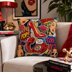 May include: A square throw pillow featuring a vibrant pop art collage with comic book style illustrations of a red high heel shoe, a rotary telephone, a lipstick tube, and stylized faces with text bubbles reading WOW, POP, COOL, and RING RING, BABY.