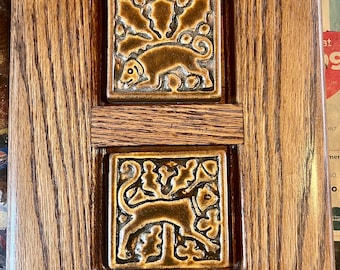 Azulejos con motivos de perros y gatos de la marca Motawi, enmarcados en roble estilo misión.