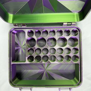 May include: An open rectangular storage case featuring a vibrant purple and green gradient finish. The interior contains a large rectangular compartment, a smaller rectangular section, and a grid of twenty-four circular holes for storage.