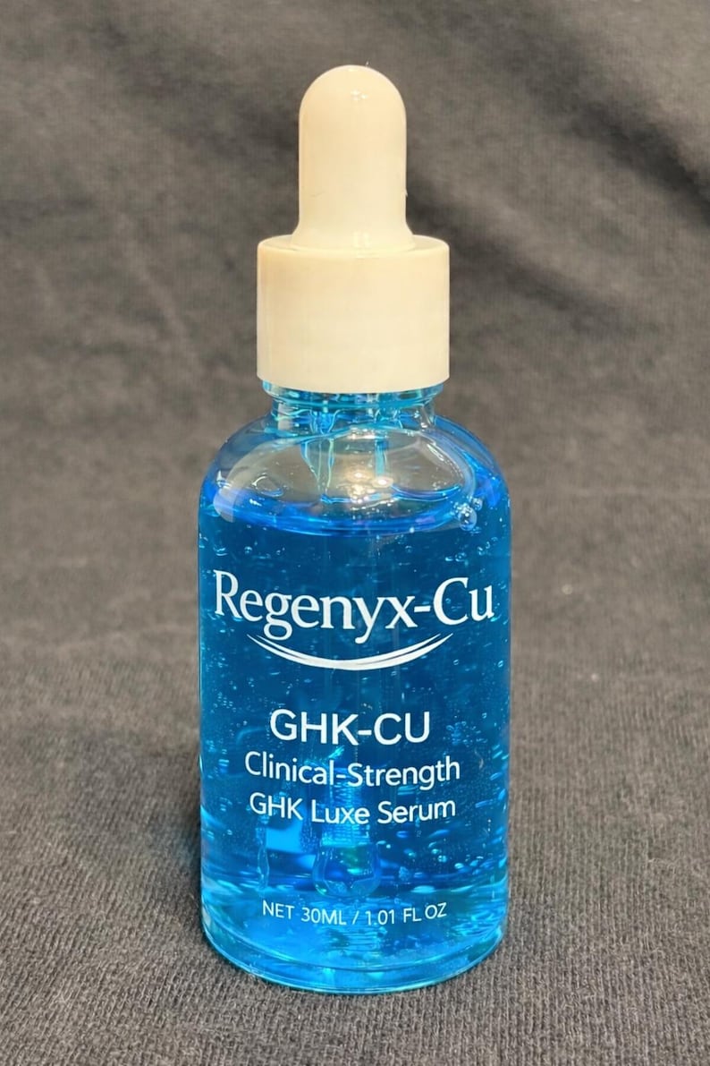 May include: A clear glass bottle filled with a vibrant blue liquid, featuring a white dropper top. The bottle is labeled "Regenyx-Cu GHK-CU Clinical-Strength GHK Luxe Serum". The bottle contains 30ml / 1.01 fl oz of serum.