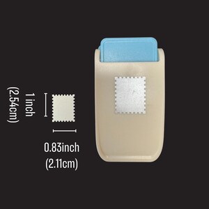 May include: A beige and light blue craft paper punch with a rectangular body and a lever mechanism. The punch creates a stamp-shaped cutout measuring 1 inch (2.54 cm) in height and 0.83 inches (2.11 cm) in width, as indicated by the text.