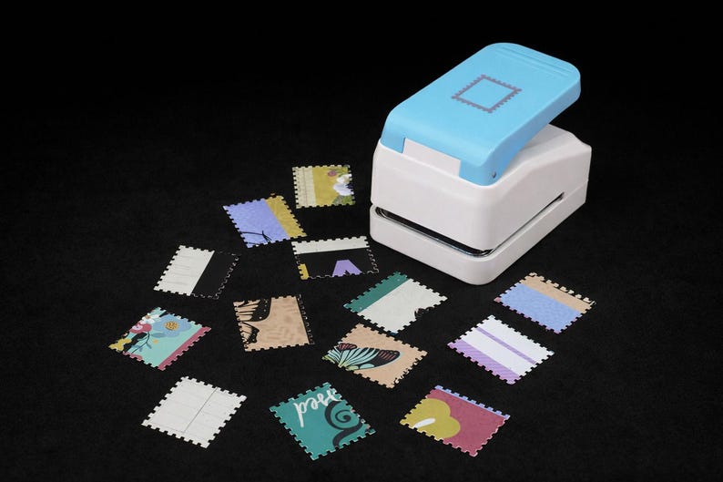May include: A light blue and white paper punch tool with a square stamp-shaped icon on top, accompanied by several small, square paper cutouts with scalloped edges featuring various colorful patterns and designs.