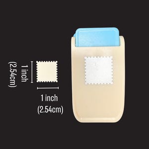 May include: A beige and light blue paper punch tool that creates a square shape with scalloped edges. The tool is shown next to a diagram indicating the punched shape measures 1 inch by 1 inch, providing a clear visual reference for size.