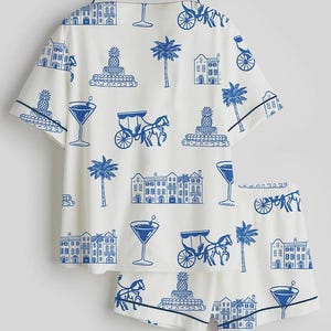 K&ouml;nnte beinhalten: Wei&szlig;es Pyjama-Set mit blauem Aufdruck mit Cocktails, Kutschen, Geb&auml;uden, Palmen und Ananas. Das Set besteht aus einem kurz&auml;rmeligen Hemd und passenden Shorts mit marineblauen Paspeln.