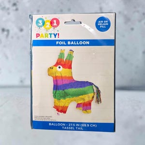 May include: A foil balloon in the shape of a multi-colored donkey piñata with a tassel tail, packaged in a white cardboard sleeve labeled 3 2 1 PARTY! and FOIL BALLOON. The packaging indicates a size of 27.5 inches and air or helium fill.