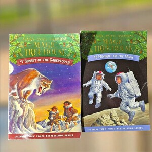May include: Two children's books from the Magic Tree House series. The first book, "Sunset of the Sabertooth," features a saber-toothed tiger. The second book, "Midnight on the Moon," shows astronauts on the moon. Both books are from the #1 New York Times Bestselling Series.