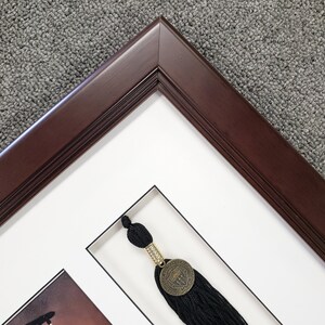May include: A dark brown wooden picture frame with a white mat and a black tassel with a gold medallion. The medallion has a design of a university seal.