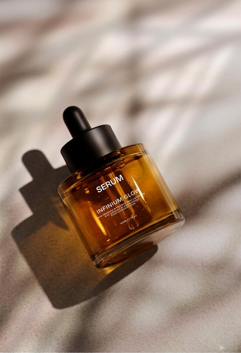 Puede incluir: Botella de s&eacute;rum color &aacute;mbar con tap&oacute;n cuentagotas negro. La botella est&aacute; etiquetada como "SERUM" e "INFINIUM GLOW". El producto est&aacute; en &aacute;ngulo, proyectando una sombra sobre una superficie de tono neutro. La botella contiene 50 ml de s&eacute;rum.