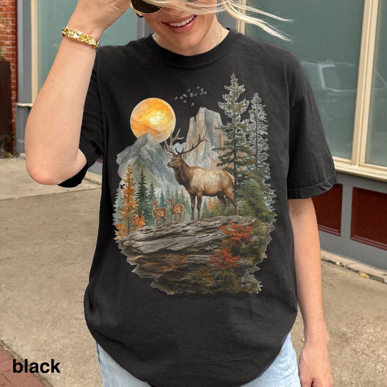 K&ouml;nnte beinhalten: Schwarzes T-Shirt mit einem detaillierten Naturmotiv. Es zeigt einen majest&auml;tischen Elch, Berge und einen Vollmond. Die Grafik umfasst B&auml;ume und andere Wildtiere, f&uuml;r eine Vintage-Outdoor-&Auml;sthetik.