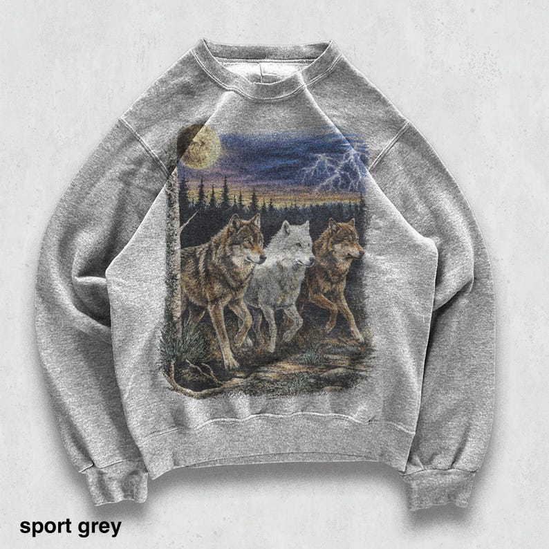 May include: Sport grey sweatshirt featuring a detailed graphic of three wolves in a forest scene under a moonlit sky with lightning. The text "sport grey" is printed at the bottom. The sweatshirt has a crew neck and long sleeves.