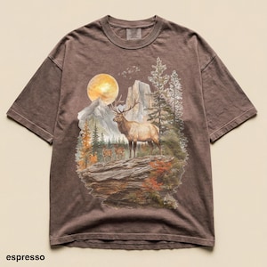 K&ouml;nnte beinhalten: Espressofarbenes T-Shirt mit Berg- und Elch-Grafik. Das Design zeigt einen Elch, B&auml;ume, Berge und einen Vollmond. Das Shirt hat kurze &Auml;rmel und einen Rundhalsausschnitt.