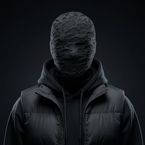 Op de afbeelding: Een persoon draagt een zwart masker met een distressed, getextureerd patroon, een zwarte hoodie, een zwart gewatteerd vest en een zwarte coltrui. De afbeelding is tegen een donkere achtergrond geplaatst, waardoor een monochromatische esthetiek ontstaat.