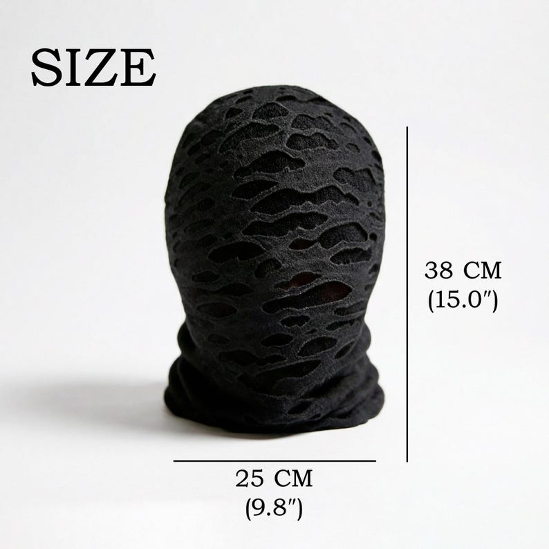 Op de afbeelding: Zwarte bivakmuts met een versleten, verscheurd ontwerp. De bivakmuts is 25 cm breed en 38 cm hoog. Het woord "SIZE" staat bovenaan gedrukt. Dit item is geschikt voor cosplay of mode.