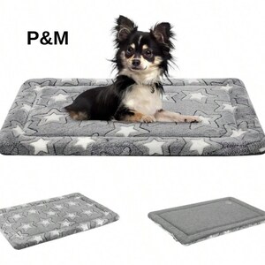 May include: A small, black, white, and brown Chihuahua dog rests on a grey pet bed with white star patterns. The bed is rectangular with a soft, plush texture. The letters "P&M" are in the upper left corner.