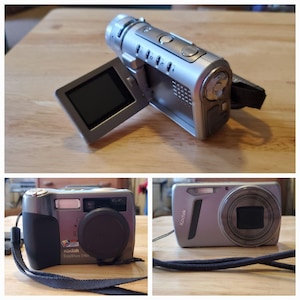 May include: A collection of three digital cameras and camcorders. The top item is a silver camcorder with a flip-out screen. Below are two Kodak digital cameras, one black and gray, the other silver.