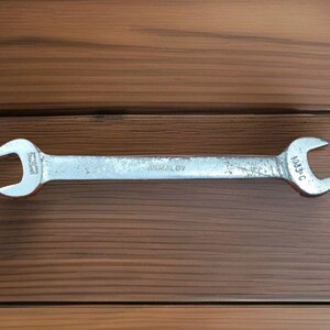 May include: A silver-colored metal double open-ended wrench with the text ARMALOY and 1083-C stamped on the surface. The tool features two open jaws of different sizes at each end of the straight, flat handle, showing signs of wear.