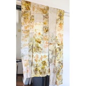 Puede incluir: Un gran tapiz textil rectangular compuesto por varios paneles de tela verticales cosidos entre sí. La tela presenta un estampado botánico orgánico con tonos variados de amarillo mostaza, verde oliva y crema en toda su superficie.