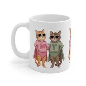 May include: A white ceramic mug with a black handle and the text "But First, Coffee" in a black, bold font. The mug is on a wooden surface. The mug is 10 cm tall.