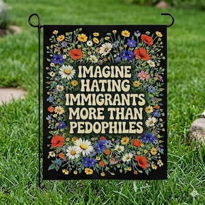 Può includere: Bandiera da giardino nera con la scritta bianca "IMAGINE HATING IMMIGRANTS MORE THAN PEDOPHILES". La bandiera è circondata da un bordo floreale di fiori colorati, tra cui margherite, papaveri e altri fiori selvatici. La bandiera è esposta in un giardino erboso.