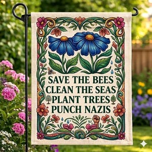 May include: A garden flag with a floral design and the text "SAVE THE BEES CLEAN THE SEAS PLANT TREES PUNCH NAZIS". The flag features two blue flowers, a bee, and various other flowers in shades of pink, orange, and green.