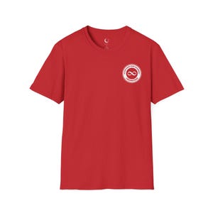 Puede incluir: Camiseta roja con un gráfico circular blanco en el pecho. El gráfico presenta un símbolo de infinito y las palabras "ACCEPTANCE OVER AWARENESS" y "FREDINSTEAD". Un pequeño logotipo de media luna está en el escote.