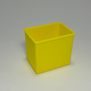 May include: A bright yellow rectangular container with a smooth surface. The container has a square shape and is empty. The item is likely a storage bin or organizer.
