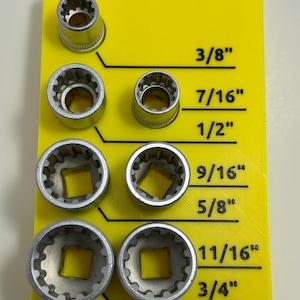 May include: A yellow holder with six silver socket wrenches of varying sizes, labeled 3/8", 7/16", 1/2", 9/16", 5/8", 11/16", and 3/4". The wrenches are arranged in two columns, with the sizes clearly marked on the yellow background.