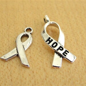 May include: Two silver ribbon charms, one with the word "HOPE" engraved on it.