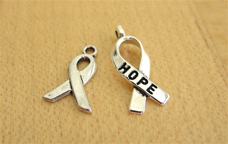 May include: Two silver ribbon charms, one with the word "HOPE" engraved on it.