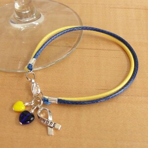 May include: A yellow and blue cord bracelet with a silver charm that says "HOPE" and two heart-shaped beads, one yellow and one blue.