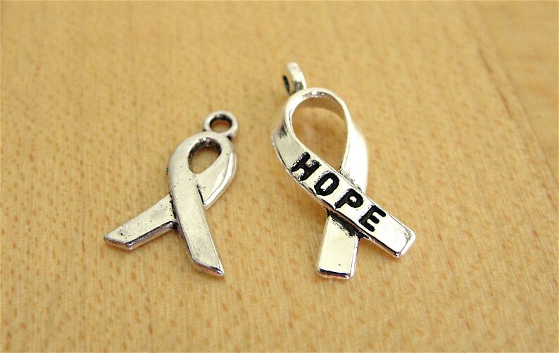 May include: Two silver ribbon charms, one with the word "HOPE" engraved on it.